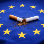 Eine zerbrochene Zigarette liegt im Sternenkreis der EU-Flagge – Symbol für den politischen Streit um die Tabaksteuer und den Verdacht koordinierter Einflussnahme auf die Konsultation der EU-Kommission.