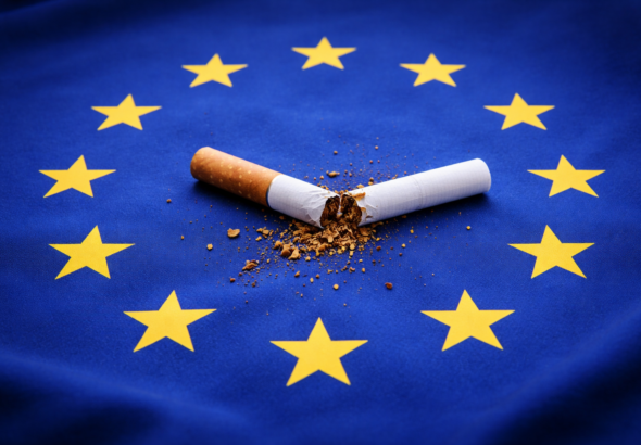 Eine zerbrochene Zigarette liegt im Sternenkreis der EU-Flagge – Symbol für den politischen Streit um die Tabaksteuer und den Verdacht koordinierter Einflussnahme auf die Konsultation der EU-Kommission.